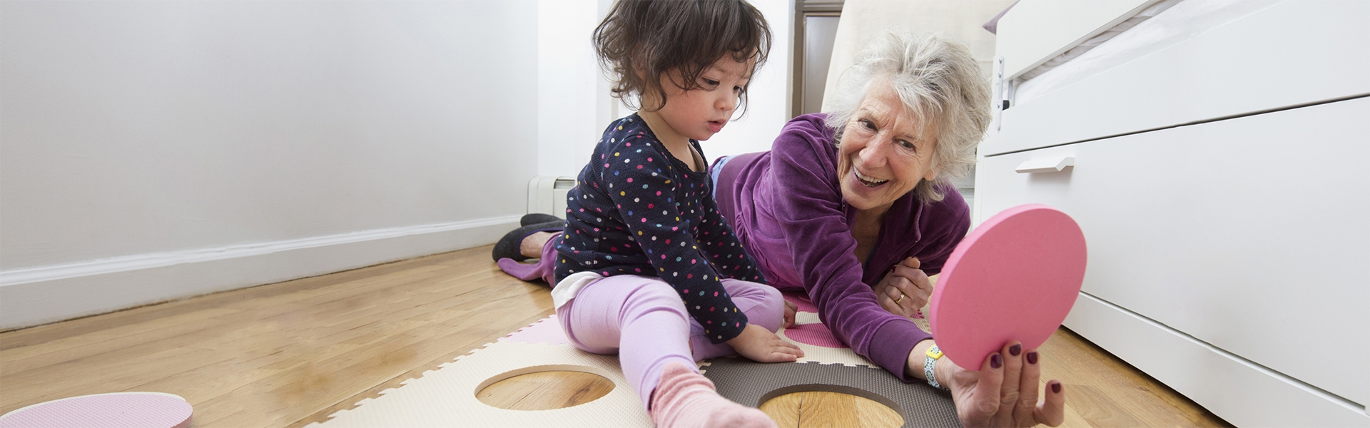 Happy grandmother playing with granddaughter on floor
