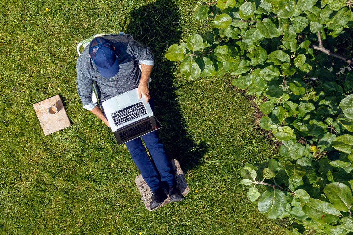 man sitting on patio using laptop 