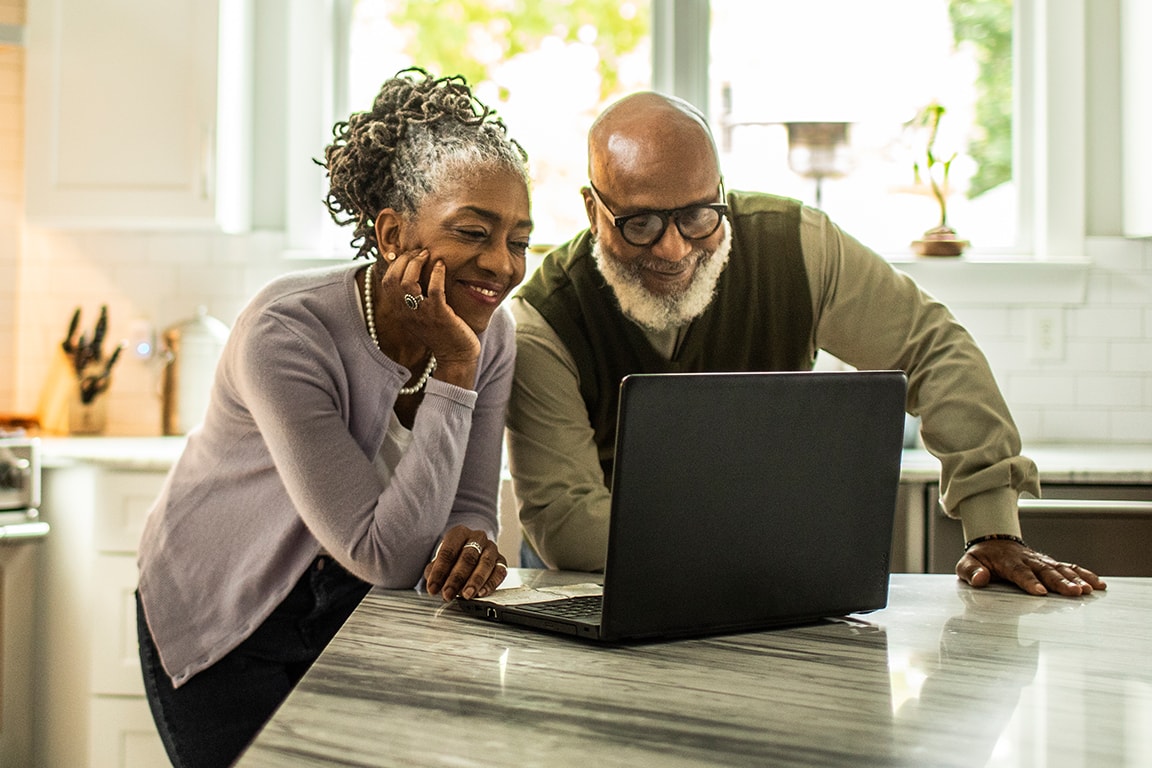 couple smiling looking at laptop