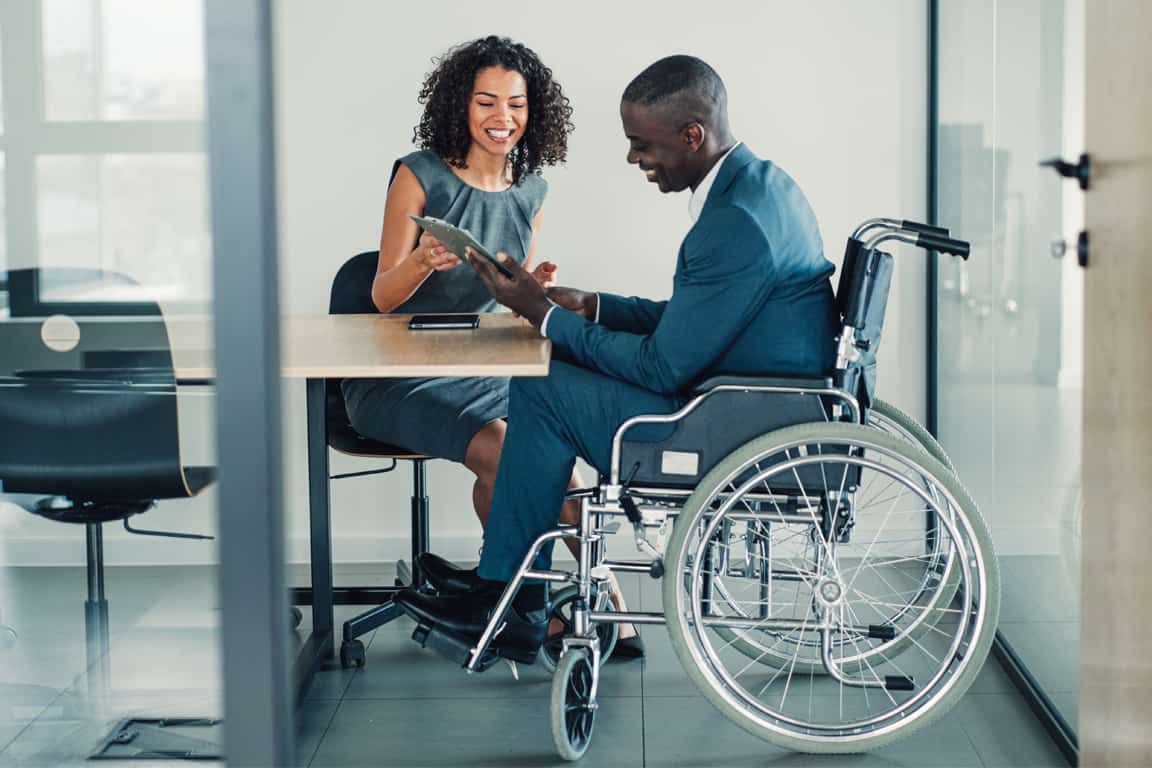 african businessman in suit sitting in wheelchair at office