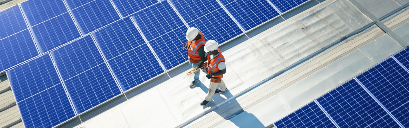 Two workers walking on the roof with solar panels