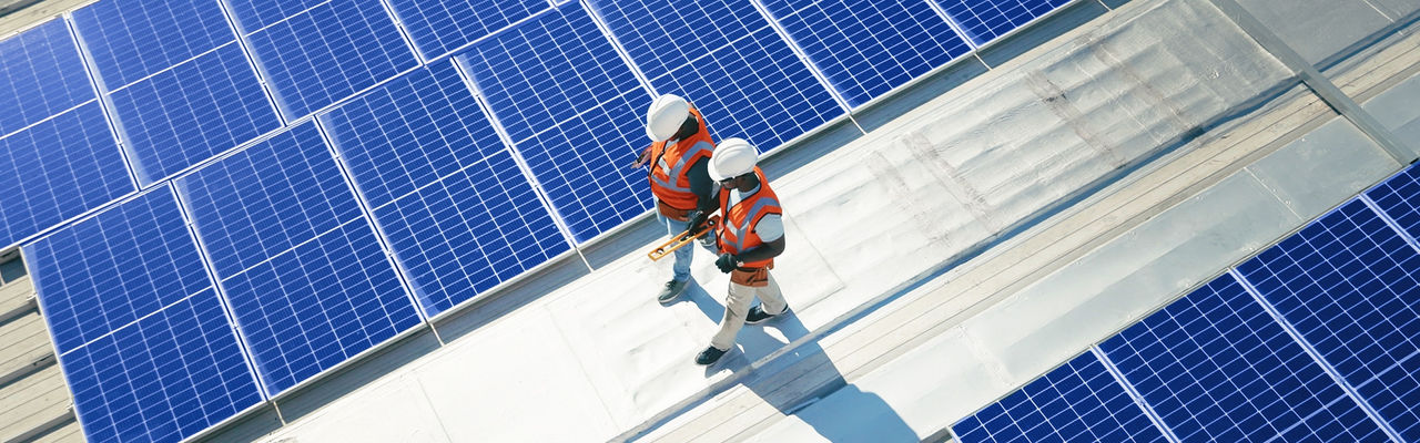 Two workers walking on the roof with solar panels