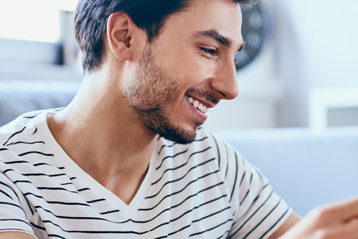 male smiling while looking at phone