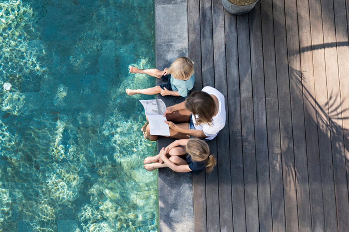 Mother and kids sitting by the pool