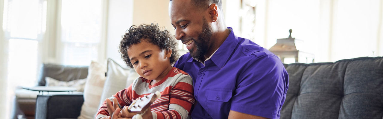 a father and his child playing guitar