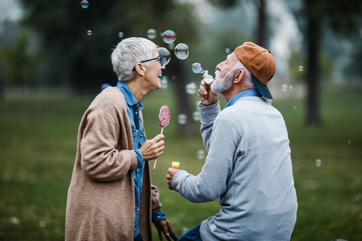 Happy mature couple having fun with bubbles in park
