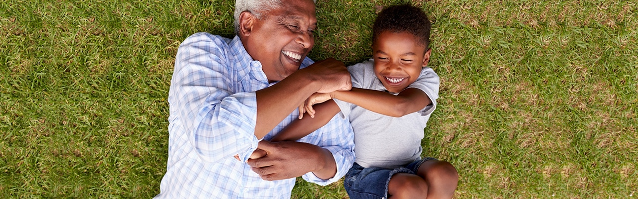 father and son laughing while laying in the grass