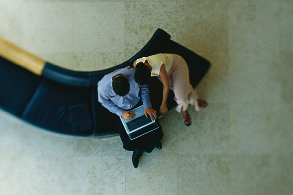 couple sitting on sofa with laptop