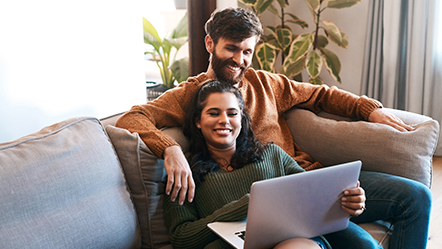 Young couple relaxing on couch looking at computer