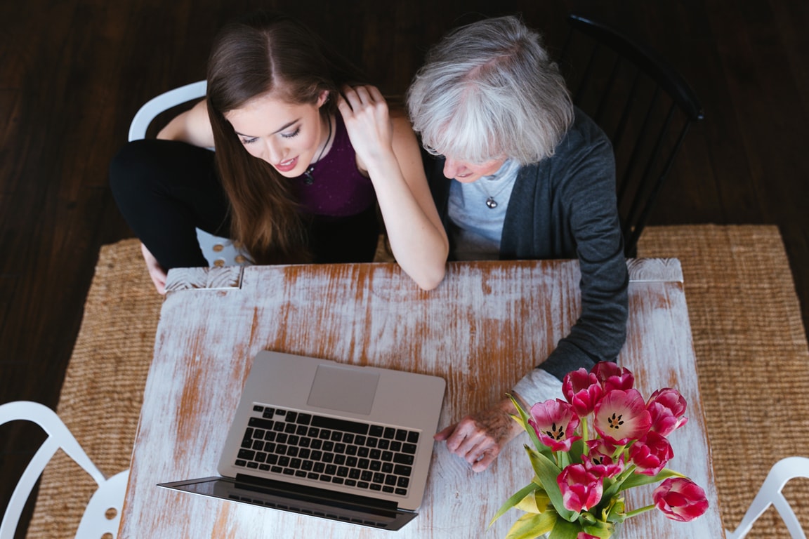 mother and daughter sitting at table looking at a computer