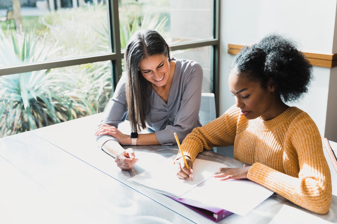 Two women writing in notebook