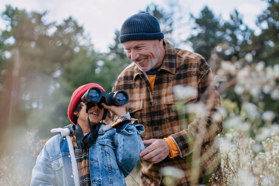 father and son in woods with binoculars