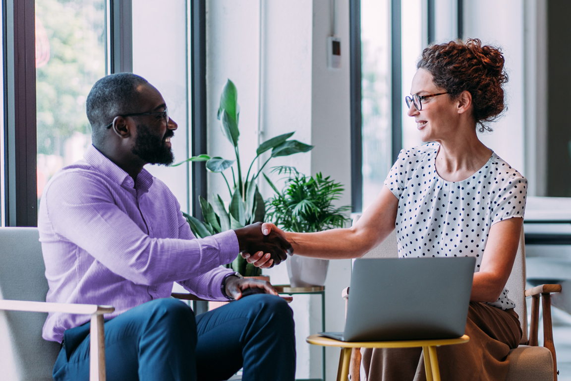 A woman and man shake hands in a corporate setting