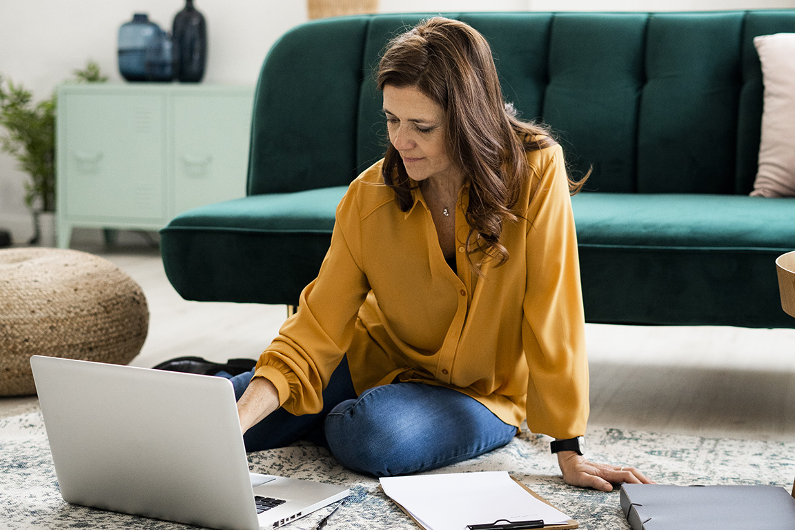 Woman typing on her laptop while sitting on the floor