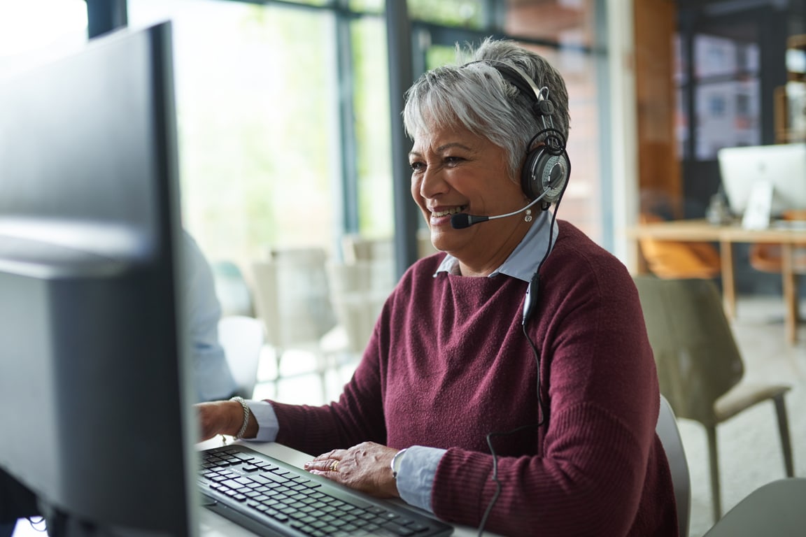 woman with headset on in front of a computer