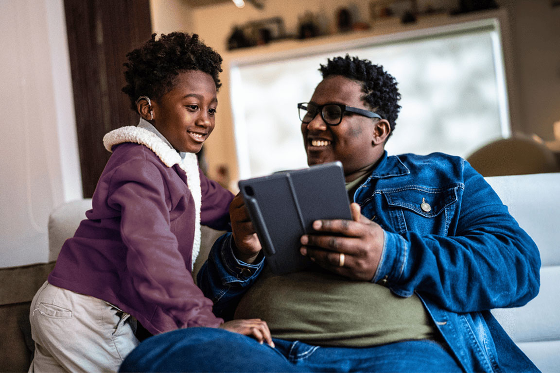 A son and father look at a mobile tablet